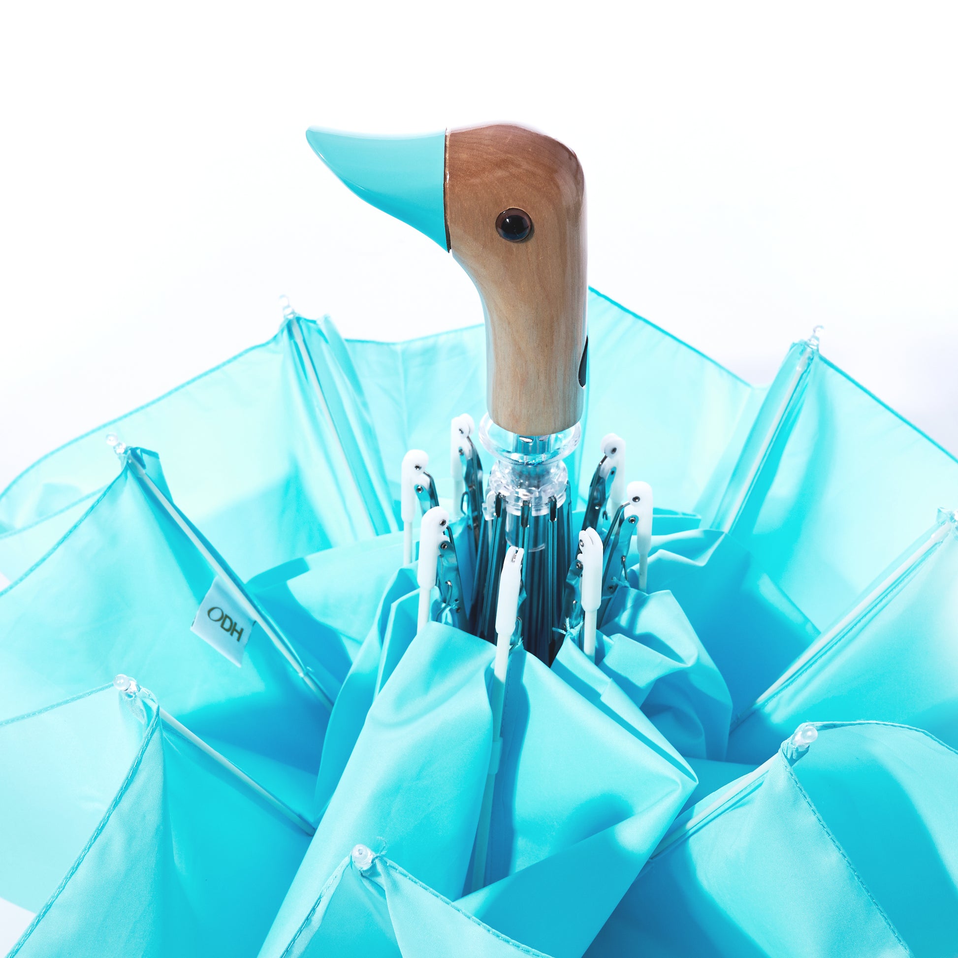 The Original Duck Head Umbrella - Popsicle Blue by ODH Limited t/a Original Duckhead features a turquoise canopy and a handle shaped like a duck’s head and beak, shown partially opened against a white background. Both charming and practical, this wind resistant umbrella adds playful style to rainy days.