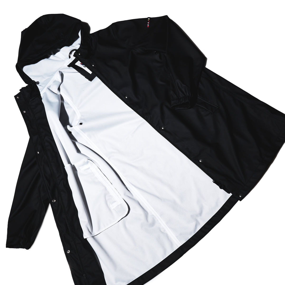 The Harborside Waterproof Raincoat - Black by Batela USA Inc is laid flat open, showing its white lining and inner pocket—perfect for coastal adventures, sleeves extended.