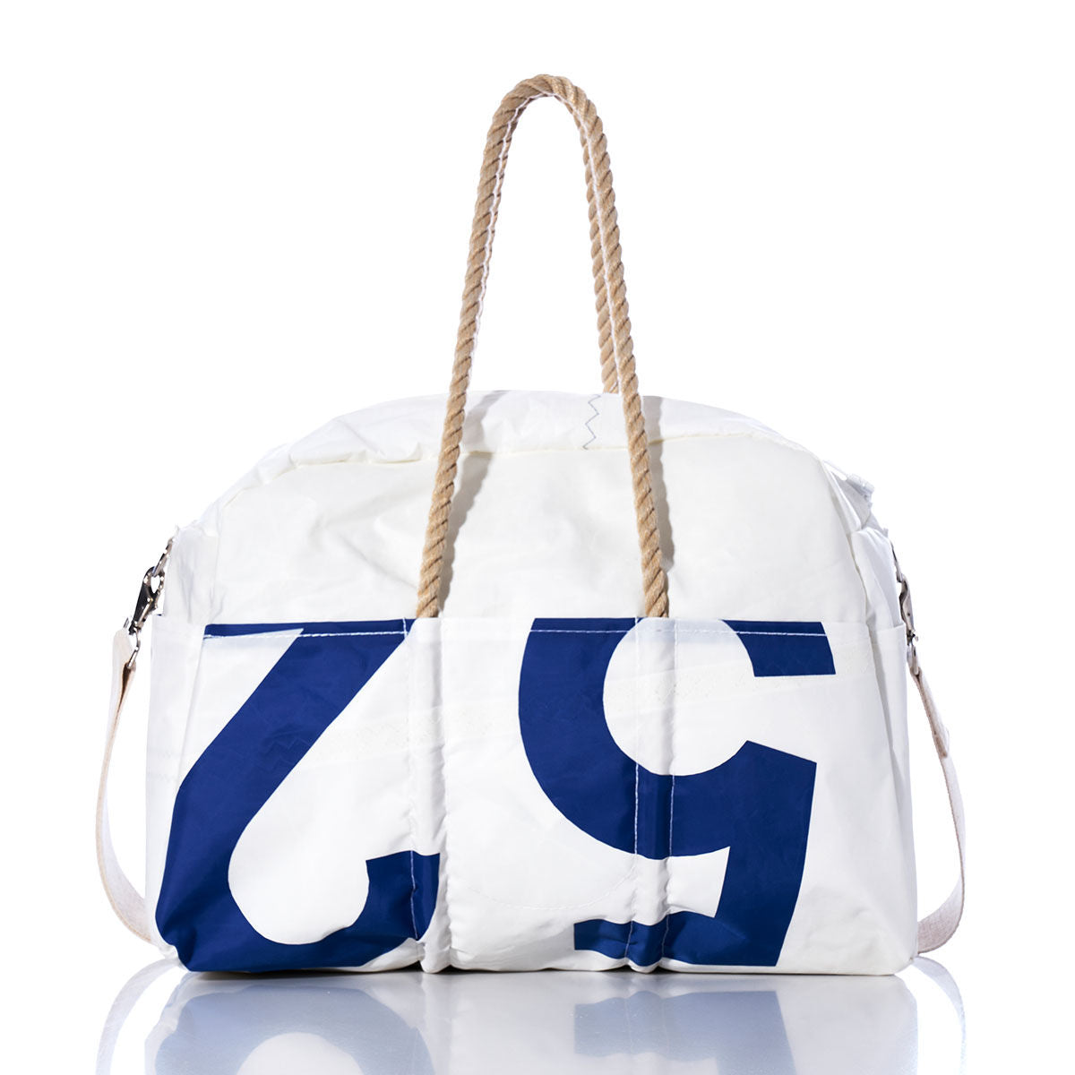 The Sea Bags Vintage US 52 Weekender, featuring blue numbers, rope handles, and a beige strap, is photographed on a white background with its reflection visible below. by Sea Bags