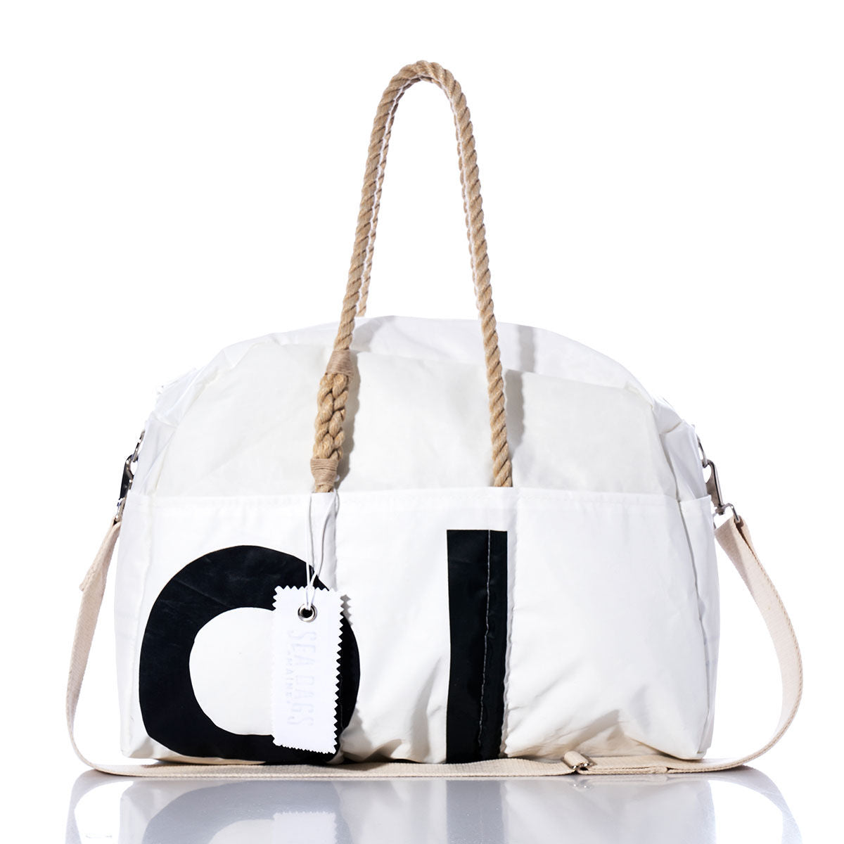Sea Bags Vintage Black 91 Weekender, a white bag featuring bold vintage black 91 numbers, tan rope handles, a beige shoulder strap, and a white tag attached, is photographed on a reflective surface. by Sea Bags