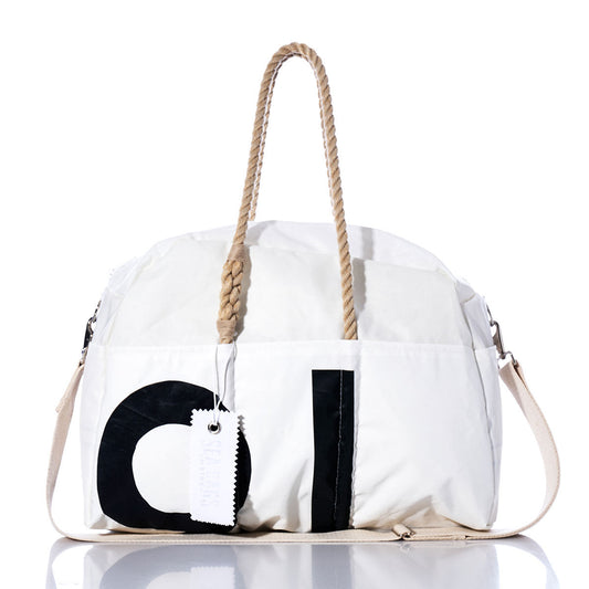 Sea Bags Vintage Black 91 Weekender, a white bag featuring bold vintage black 91 numbers, tan rope handles, a beige shoulder strap, and a white tag attached, is photographed on a reflective surface. by Sea Bags