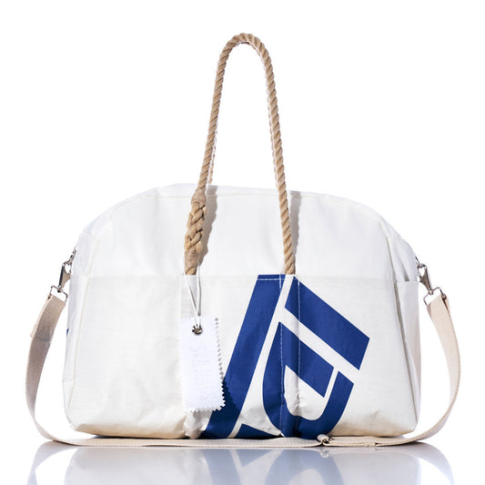 The Sea Bags Vintage Ideal 18 Weekender features a white design with tan hemp handles, a blue geometric print, a detachable shoulder strap, and a white tag, displayed on a white background—perfect as your next getaway bag. by Sea Bags