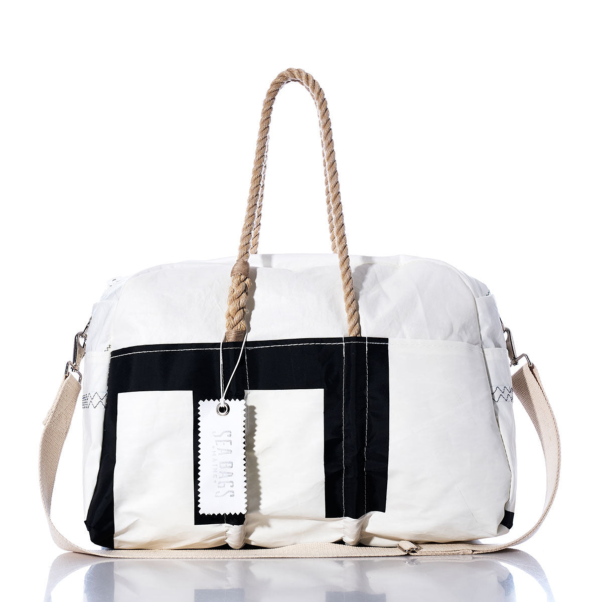 The Sea Bags Vintage Etchells 22 Weekender is a white and black duffel getaway bag featuring sturdy hemp handles, a beige shoulder strap, and a white tag reading SEABAGS, photographed on a white background. by Sea Bags