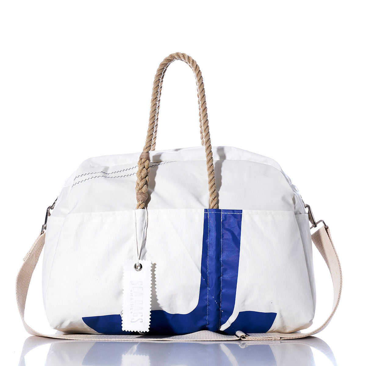 Introducing the Sea Bags Vintage JY Weekender—a white duffel bag featuring blue accents, tan rope-like hemp handles, and a beige shoulder strap, elegantly displayed on a reflective surface. The perfect vintage-inspired weekender for your next getaway. by Sea Bags