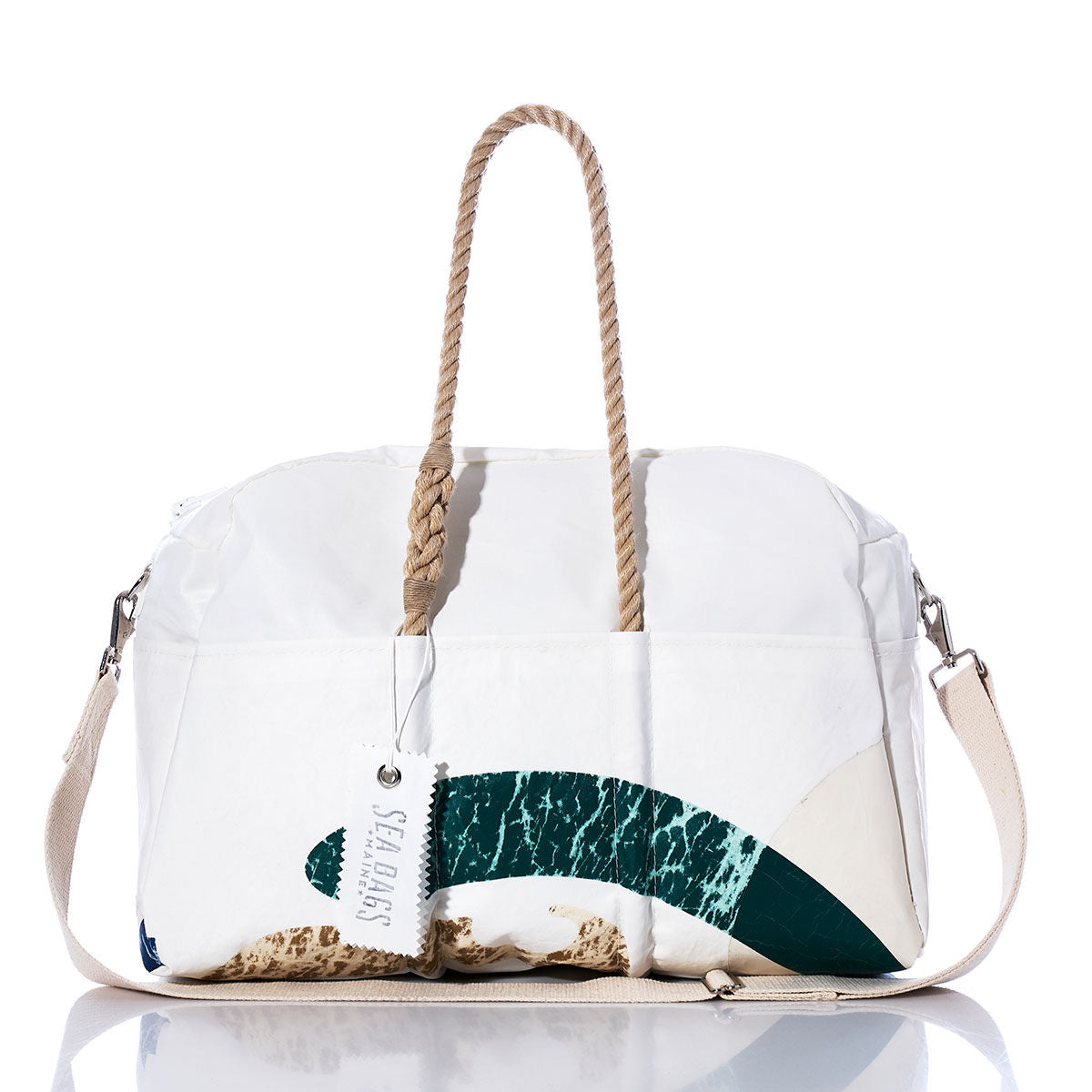 Introducing the Vintage Seahawk Weekender by Sea Bags—a white duffel bag featuring tan rope handles, a detachable beige shoulder strap, and an eye-catching green and tan wave design. Perfect for your next getaway, this stylish weekender is finished with a white SEA BAGS tag on one handle that adds a hint of vintage charm. by Sea Bags