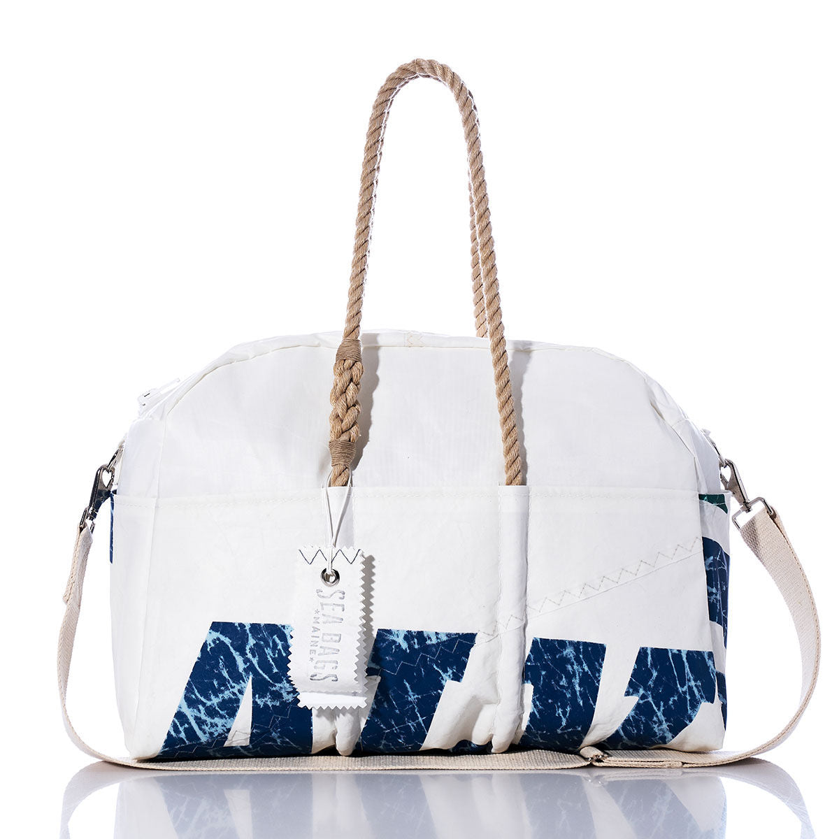 The Vintage Salve Sailing Weekender by Sea Bags is a stylish white and blue duffel bag featuring hemp handles, a detachable shoulder strap, and a tag labeled Sea Bags attached to one handle. It is photographed against a white background. by Sea Bags