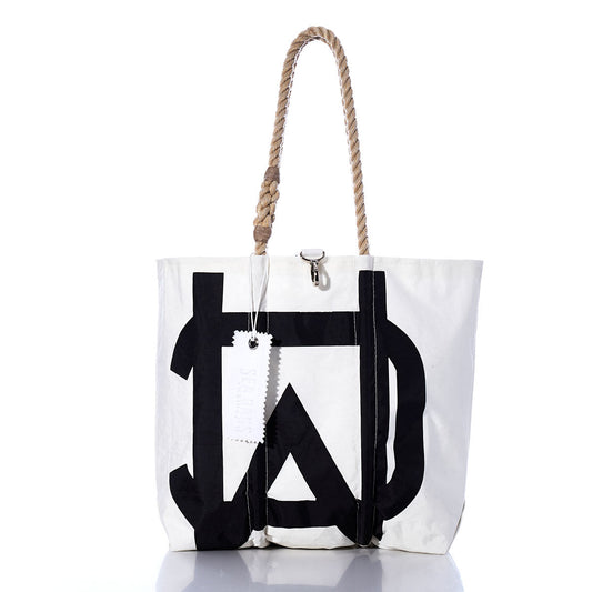 The Sea Bags Vintage Melges Medium Tote, handcrafted in Maine from sailcloth, features a white body with a bold black geometric print, sturdy rope handles, and a white tag. Displayed on a white background, this tote combines durability with timeless style. by Sea Bags