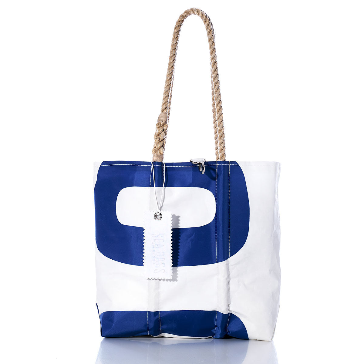 The Sea Bags Vintage Blue 00 Medium Tote features a white and blue sailcloth design with rope handles, a metal zipper, and a white tag attached, all handmade in Maine and displayed against a white background. by Sea Bags