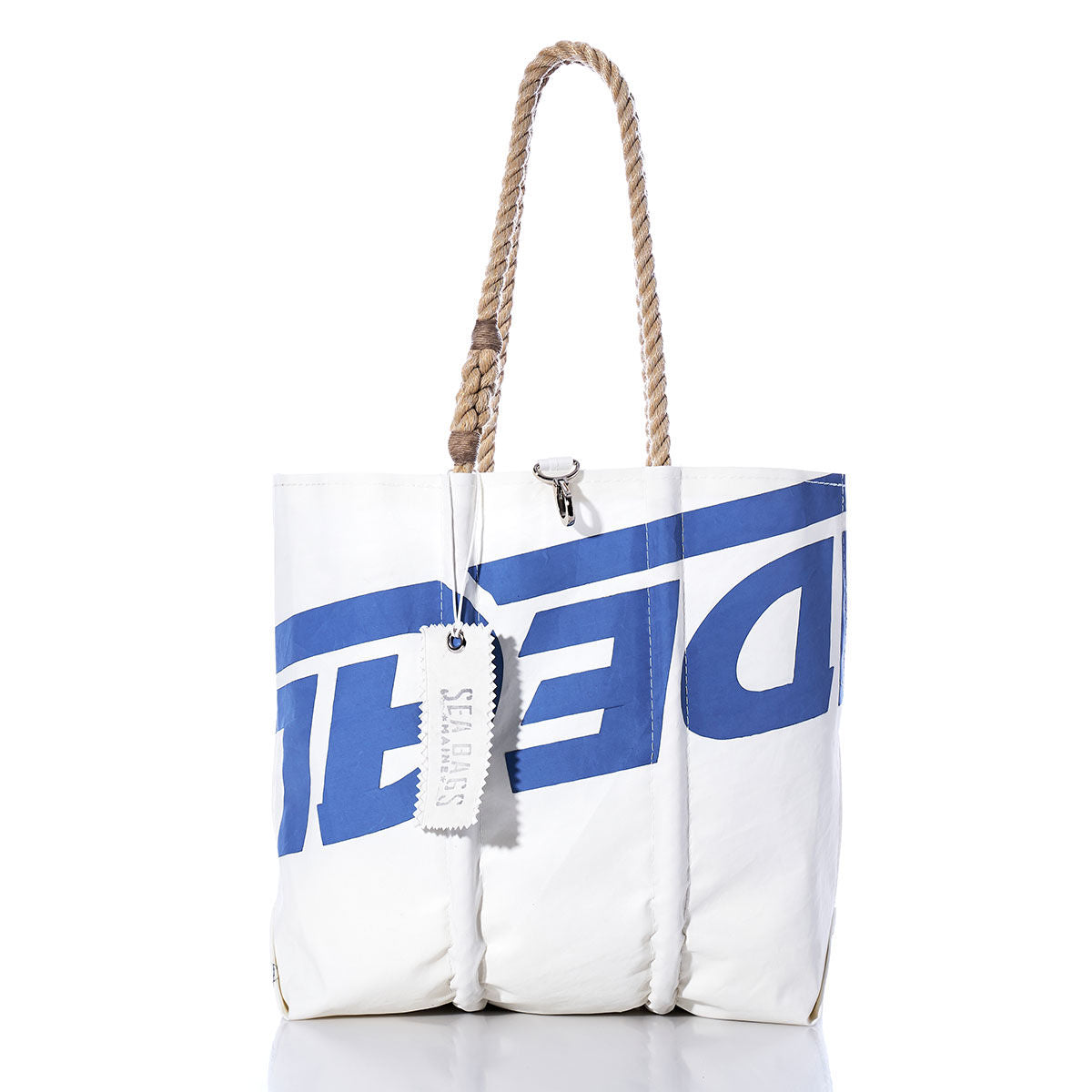 The Sea Bags Vintage Ideal 18 Medium Tote is a white bag with blue lettering, hand-spliced rope handles, and a SEA BAGS tag, photographed on a plain white background. Expertly crafted in Maine from vintage sailcloth, this tote blends coastal charm with lasting quality. by Sea Bags