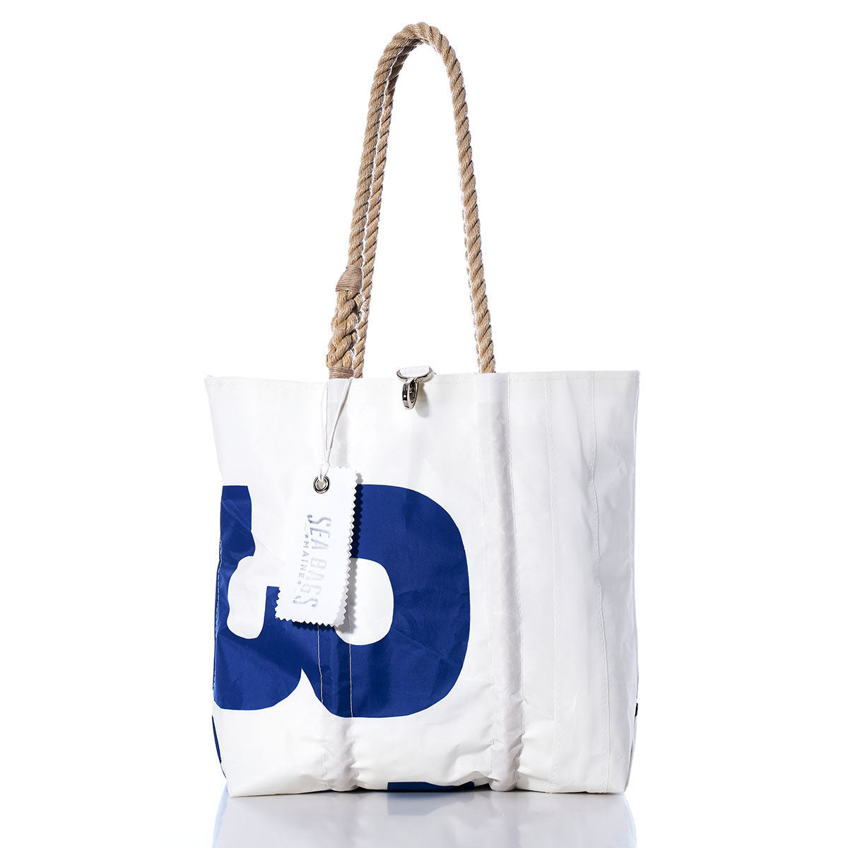 The Vintage 31 Medium Tote by Sea Bags is a white tote bag made from vintage sail material, showcasing bold blue lettering, hand-spliced rope handles, and a white Sea Bags tag attached to one handle; displayed against a white background. by Sea Bags