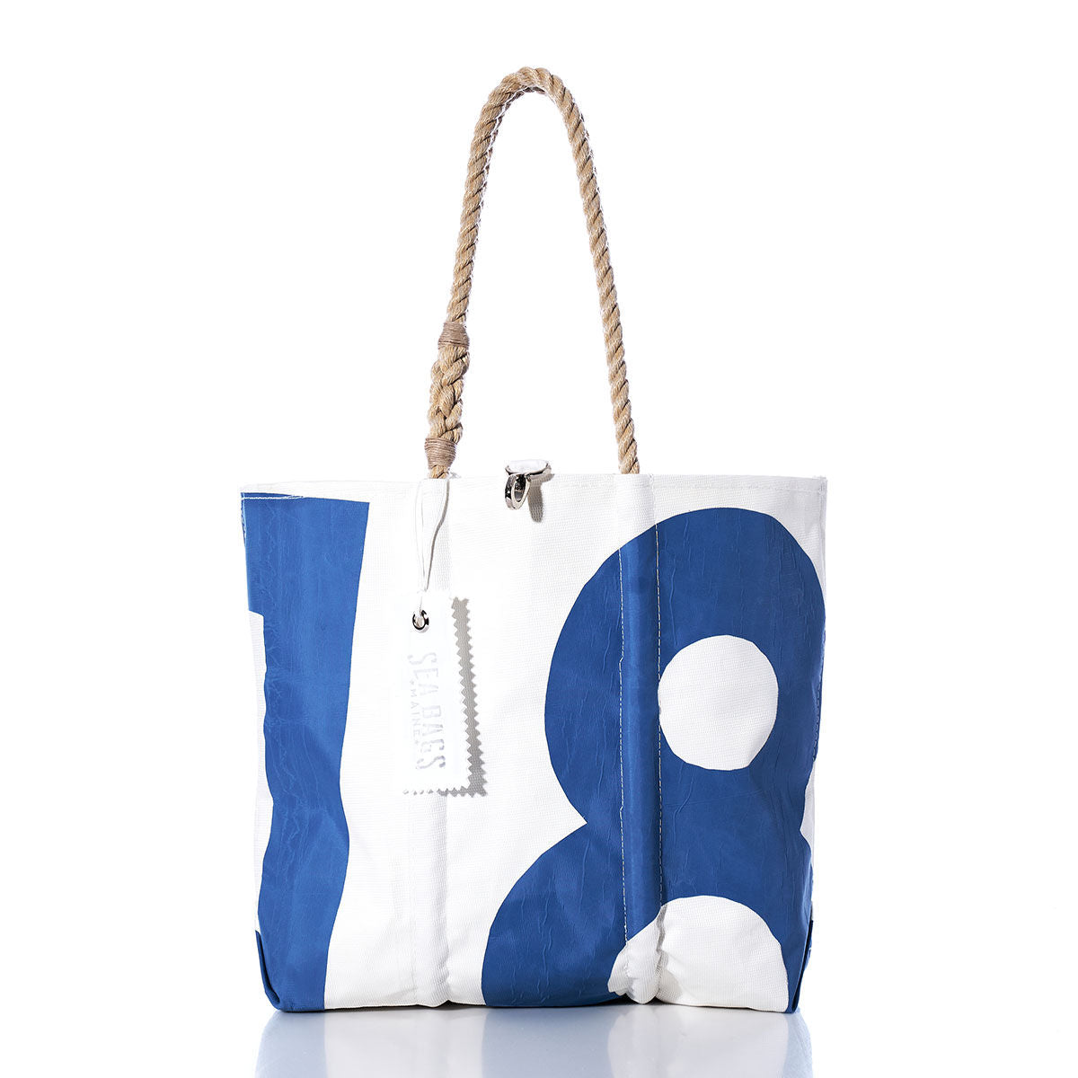 The Sea Bags Vintage 18 Medium Tote is a white tote handcrafted in Maine from durable sailcloth, featuring a bold blue number 18 design. This vintage bag includes rope handles and a rectangular white tag, and is shown on a white background. by Sea Bags