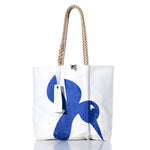 The Sea Bags Vintage Hummingbird Medium Tote showcases a blue abstract design on white sailcloth, reminiscent of classic styles. Handcrafted in Maine, this artisanal tote features sturdy rope handles and a white tag attached to one handle. The product is photographed against a white background to emphasize its authentic construction and vintage-inspired charm. by Sea Bags