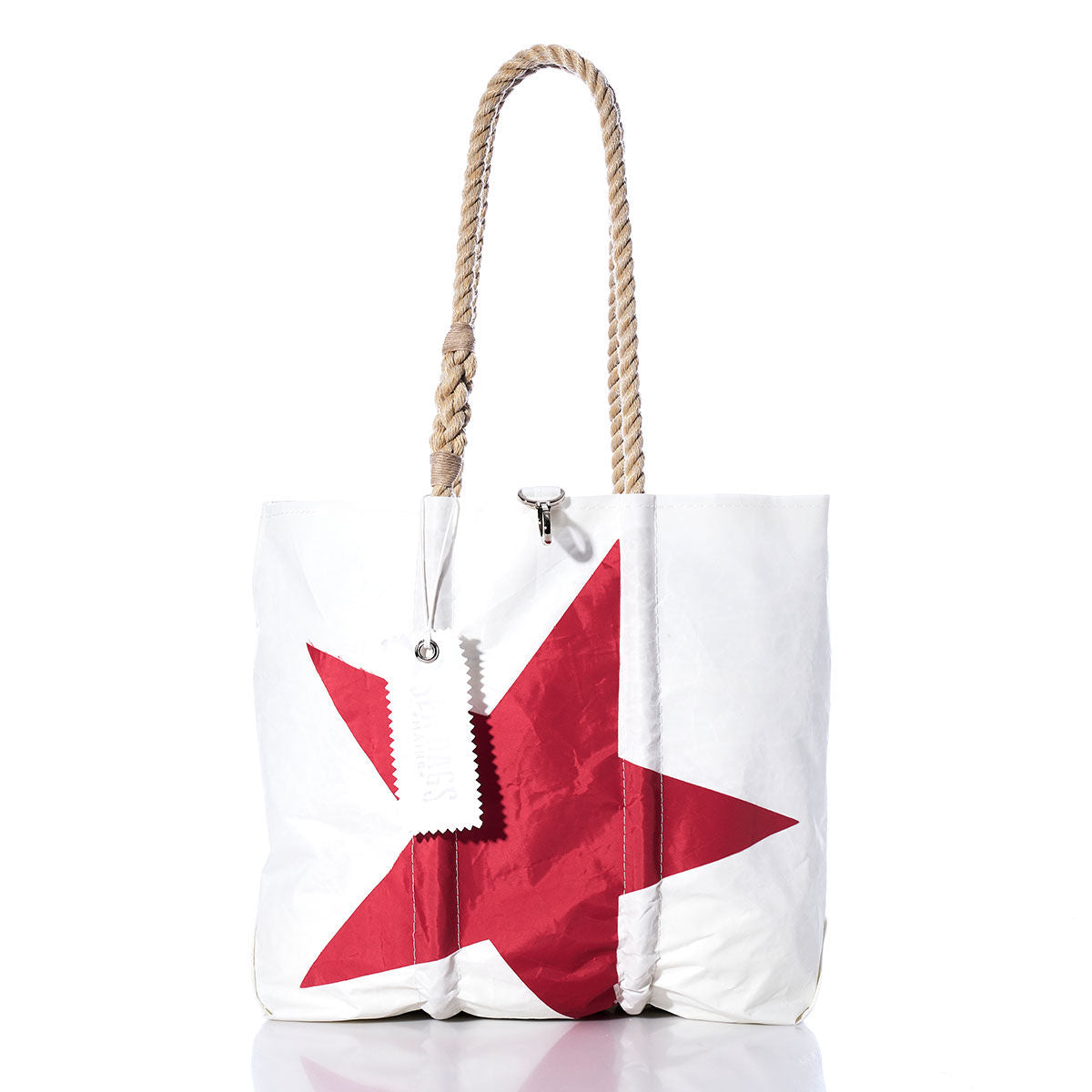 Sea Bags Vintage Red Star Medium Tote is a handmade Maine tote crafted from white sailcloth, featuring a bold red star design, sturdy rope handles, and a white tag attached. Shown against a plain white background, this bag combines classic Sea Bags style with durable materials. by Sea Bags