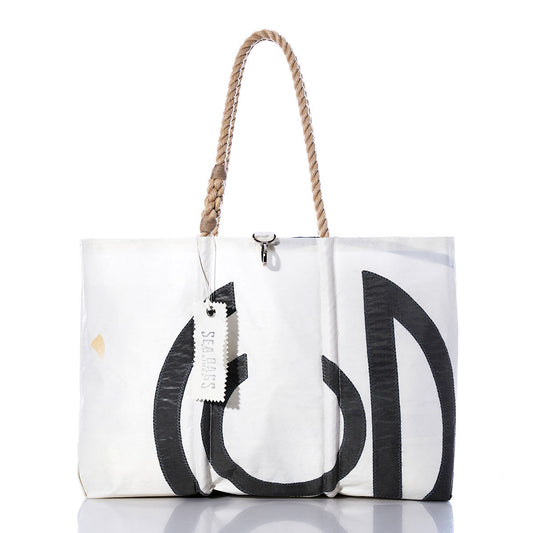 Vintage CG Large Tote by Sea Bags: This handmade sailcloth tote from Maine features black graphic accents, a rope handle, and a white tag bearing the Sea Bags name. The bag is photographed against a white background with a subtle reflection beneath it. by Sea Bags