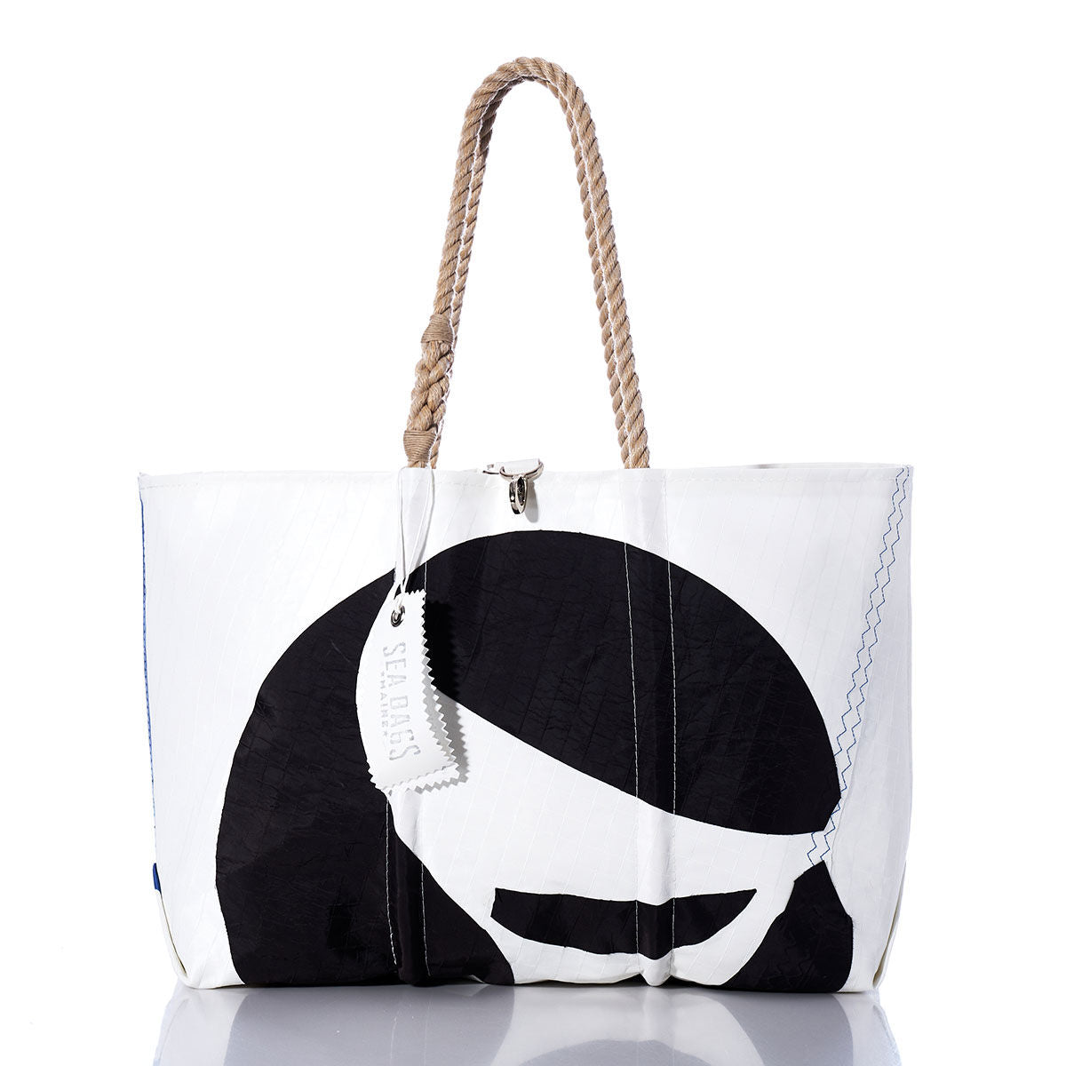 White tote bag featuring a black graphic design, rope handles, and a rectangular tag. The Sea Bags Vintage Sea Sprite Large Tote is expertly handcrafted in Maine from durable sailcloth, blending style with function. Displayed against a plain white background with a subtle reflection underneath. by Sea Bags