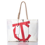 Introducing the Vintage Town Class Large Tote by Sea Bags—a white canvas bag handcrafted in Maine, distinguished by a bold red C on the front. It features hand-spliced rope handles and a signature white SEA BAGS tag on one handle, seamlessly combining style with exceptional durability. by Sea Bags