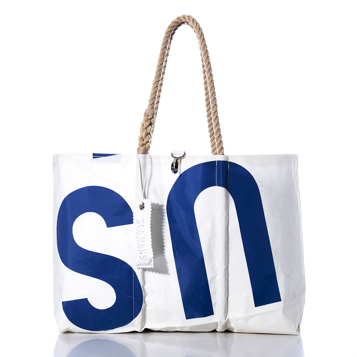 The Sea Bags Vintage US Large Tote is shown on a white background, featuring large blue S and N lettering, hand-spliced rope handles, and a white tag attached. This signature Maine-crafted bag exemplifies the brand’s classic style. by Sea Bags