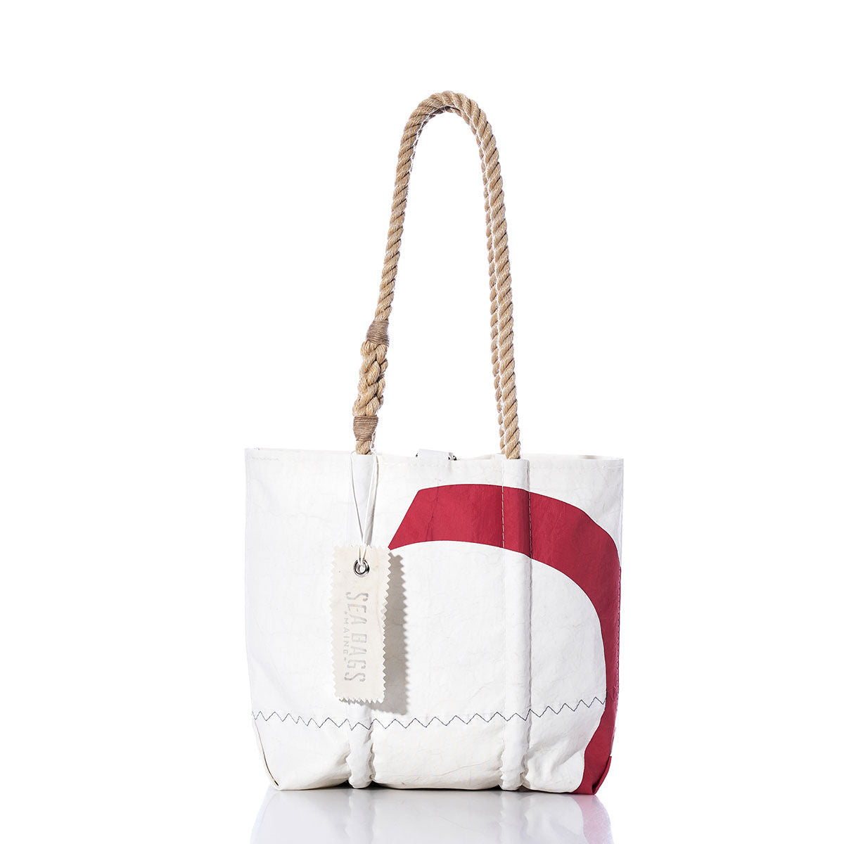 The Vintage Red 2 Handbag by Sea Bags is crafted from recycled white sailcloth and features a bold, curved red graphic inspired by classic sail insignias along the side. It’s finished with sturdy hemp rope handles and a signature Sea Bags tag on the front, offering a modern update to the timeless handbag style. by Sea Bags