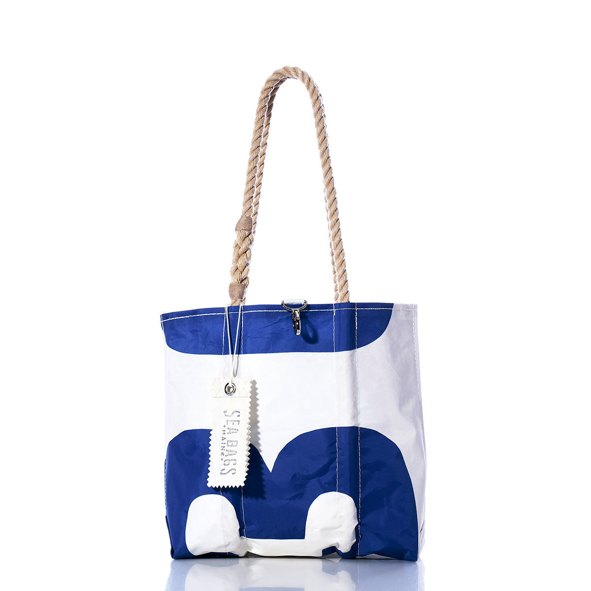 Vintage Blue 13 Handbag by Sea Bags, featuring hemp rope handles and a hanging tag with the Sea Bags logo, showcases subtle sail insignias against its blue and white design, displayed against a white background. by Sea Bags