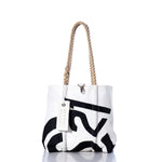 White tote bag with bold black print, hemp rope handles, and a white tag hanging from one handle, photographed on a white background with a subtle reflection below. The Sea Bags Vintage CS21 Handbag is inspired by classic sail insignias, blending timeless style with nautical flair. by Sea Bags