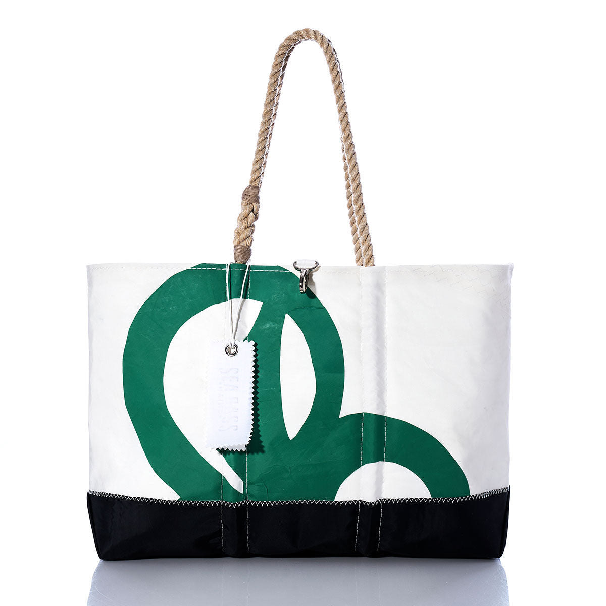 The Vintage Shannon Ogunquit Beach Tote by Sea Bags, crafted from recycled sail cloth, features a striking large green graphic, sturdy rope handles, and an attached white tag. Shown here in white and black on a reflective surface. by Sea Bags