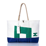 The Sea Bags Vintage Pearson 10M Ogunquit Beach Tote features a white and blue design with a green geometric pattern, expertly crafted from recycled sail cloth sourced from a vintage Pearson 10M sailboat. Complete with sturdy rope handles and an attached white tag, the tote is photographed against a white background. by Sea Bags
