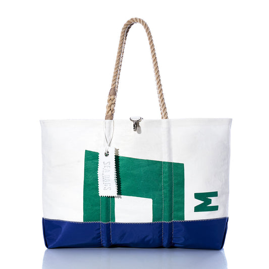 The Sea Bags Vintage Pearson 10M Ogunquit Beach Tote features a white and blue design with a green geometric pattern, expertly crafted from recycled sail cloth sourced from a vintage Pearson 10M sailboat. Complete with sturdy rope handles and an attached white tag, the tote is photographed against a white background. by Sea Bags