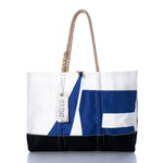 The Sea Bags Vintage Etchells Ogunquit Beach Tote features a blue and white geometric design, a black bottom, sturdy rope handles, and a SEA BAGS tag attached to one handle. Thoughtfully crafted from recycled sail cloth, this durable tote offers eco-friendly functionality with timeless style. by Sea Bags