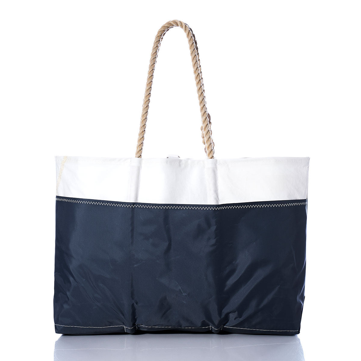 The Sea Bags Vintage Lightning Ogunquit Beach Tote features a white upper section, navy blue lower section, zigzag stitching, and two thick rope handles. Crafted from recycled sail cloth and photographed on a white background, this spacious beach bag blends style and functionality for all your seaside adventures. by Sea Bags