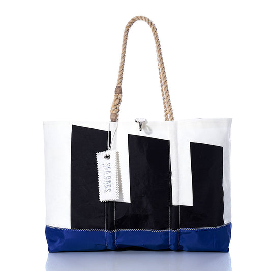 Introducing the Vintage Etchells Ogunquit Beach Tote by Sea Bags—a spacious beach tote crafted from recycled sail cloth, distinguished by its blue bottom, white upper section, bold black geometric shapes, sturdy rope handles, and signature SEA BAGS tag. This tote effortlessly blends vintage Etchells charm with modern coastal style. by Sea Bags