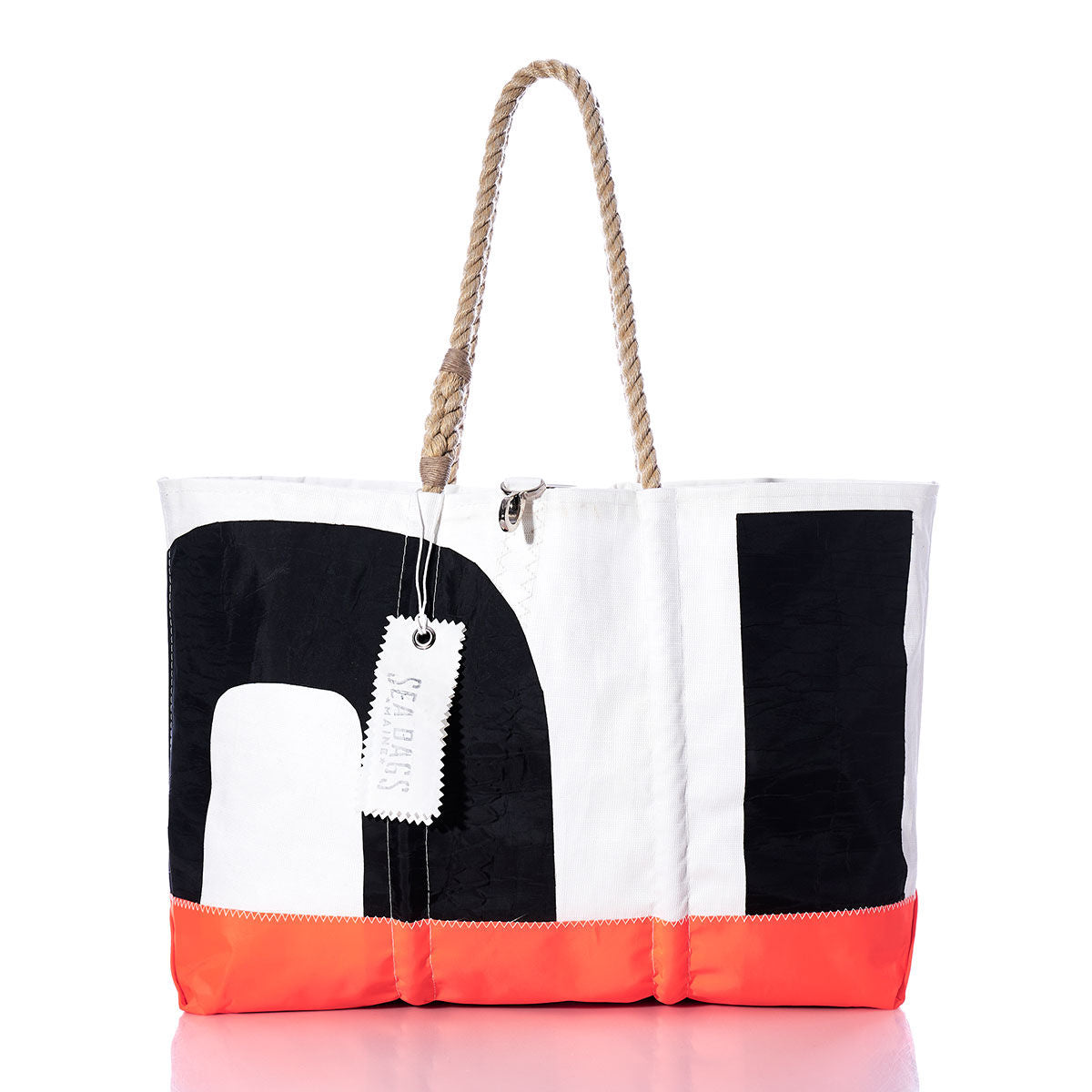 The Sea Bags Vintage Black 01 Ogunquit Beach Tote features striking black and white color blocks, an orange bottom trim, and sturdy rope handles, all crafted from recycled sail cloth. Finished with a white tag labeled “FEARLESS,” this large tote bag combines vintage sail charm with bold, practical style. by Sea Bags