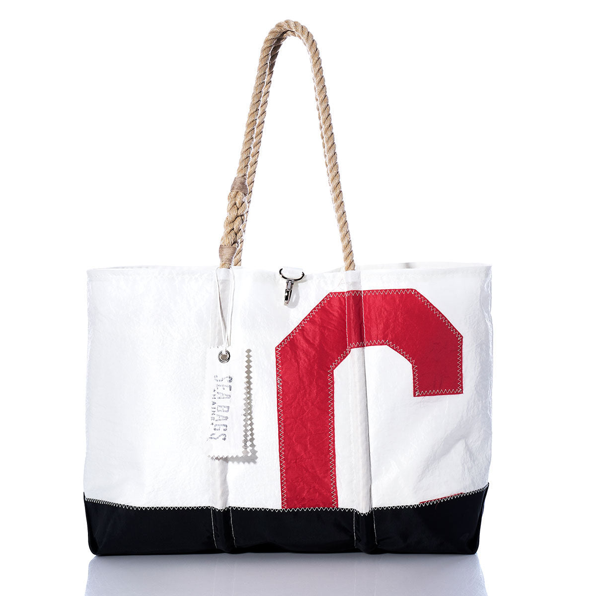 The Sea Bags Vintage Red C Ogunquit Beach Tote is a white and black beach bag with a sturdy rope handle, made from recycled sail cloth and showcasing a bold vintage red letter C on the front, photographed against a white background. by Sea Bags