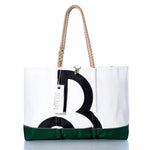 The Vintage Beneteau Ogunquit Beach Tote by Sea Bags is a white and green beach tote crafted from recycled sail cloth, featuring a bold black letter B inspired by vintage Beneteau style, rope handles, and a white Sea Bags tag near the top. by Sea Bags