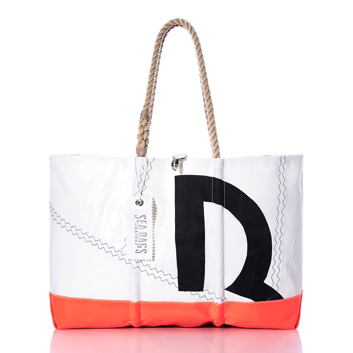 The Vintage Beneteau Ogunquit Beach Tote by Sea Bags is a white and orange beach bag crafted from recycled sail cloth, featuring rope handles, zigzag stitching, and a bold black letter R design. A SEA BAGS tag is attached near the handle for an authentic touch. by Sea Bags