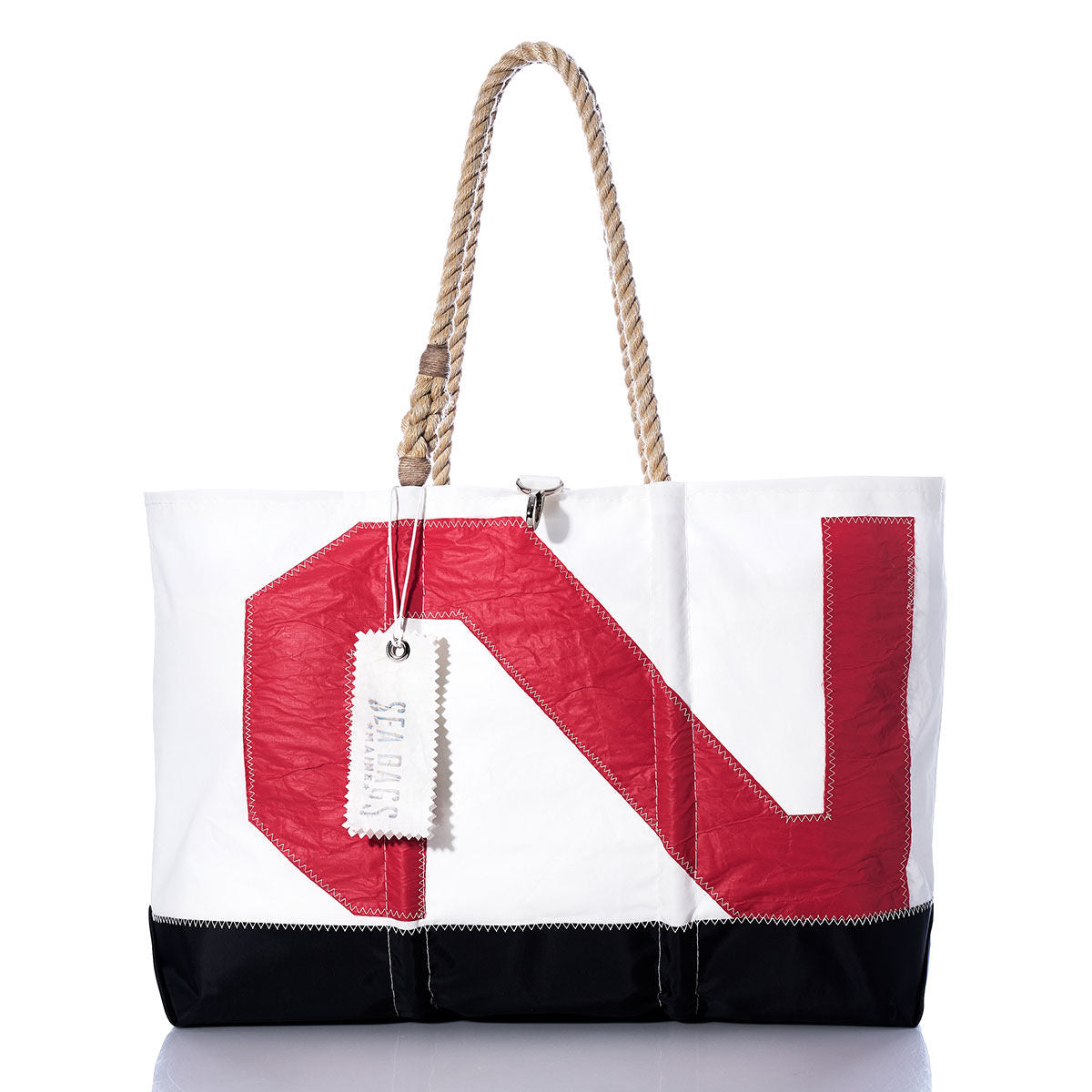 The Vintage Red 2 Ogunquit Beach Tote by Sea Bags features a white sail cloth body with a black bottom, a bold red N design, sturdy rope handles, and a signature white Sea Bags tag. Expertly crafted from recycled sail cloth, this sustainable beach bag is the perfect companion for your seaside adventures. by Sea Bags