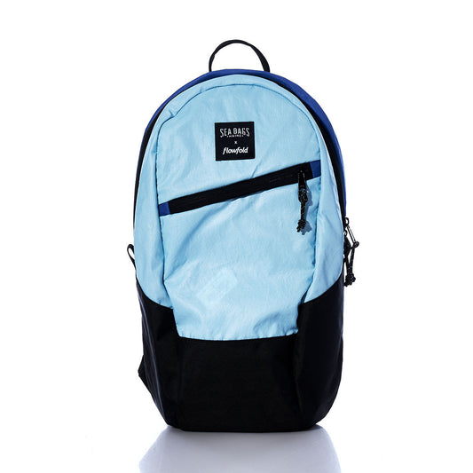 The Sea Bags Vintage Blue Crew Backpack, made from recycled sail cloth and featuring a black front zipper pocket and a top handle, is shown against a white background—an ideal sustainable choice for everyday use. by Sea Bags