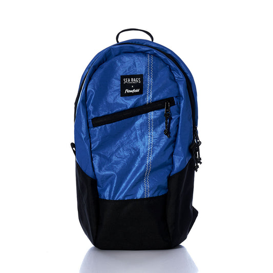 The Sea Bags Vintage Blue Crew Backpack is a sustainable blue and black backpack made from recycled sail cloth, featuring a front zipper pocket, a black bottom panel, a small top handle, and the brand label displayed near the top front. by Sea Bags