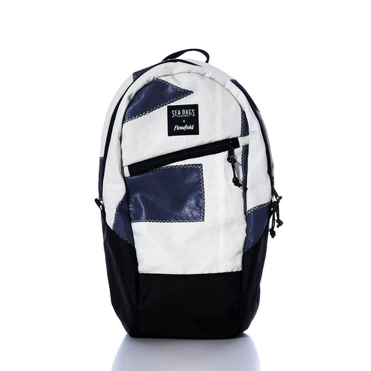Introducing the Vintage Dark Purple Crew Backpack by Sea Bags—a sustainable backpack crafted from recycled sail cloth, featuring black, white, navy, and vintage dark purple panels. It includes a front zipper pocket, convenient side pockets, and a prominently displayed “SEA BAGS x Flowfold” label, all set against a crisp white background. by Sea Bags