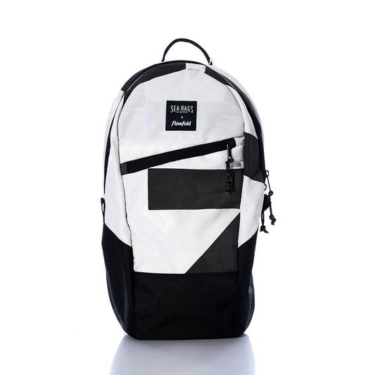 The Vintage Black and White Crew Backpack by Sea Bags is displayed against a white background. Featuring a geometric design, front zipper pocket, and a SEA BAGS x Flowfold patch, this sustainable backpack is crafted from recycled sail cloth, combining eco-friendly materials with classic style. by Sea Bags