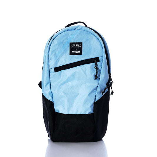 Introducing the Vintage Blue Crew Backpack by Sea Bags—a sustainable backpack crafted from recycled sail cloth in light blue and black. This eco-friendly bag features a front zipper pocket and a branded label, shown against a plain white background. by Sea Bags