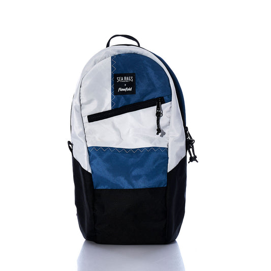 The Sea Bags Vintage Blue and White Crew Backpack is displayed standing upright against a white background. Featuring a front zip pocket and the iconic Seabags logo patch, this sustainable backpack is expertly crafted from recycled sail cloth, blending timeless style with eco-friendly materials. by Sea Bags