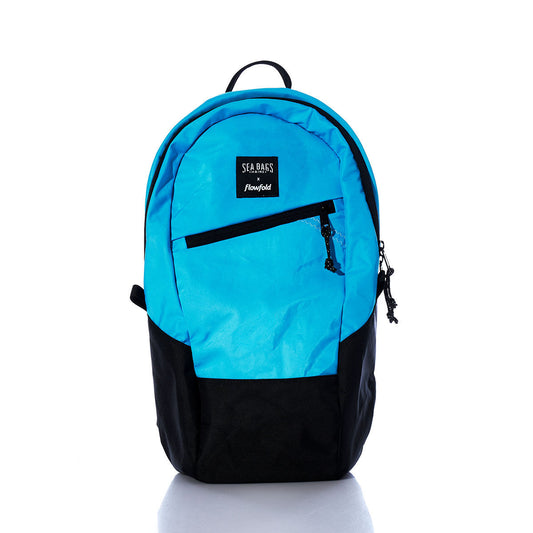 The Sea Bags Vintage Blue Crew Backpack stands upright on a white background, crafted from recycled sail cloth and featuring a front zip pocket and top handle. This sustainable backpack effortlessly blends style with eco-friendly materials. by Sea Bags