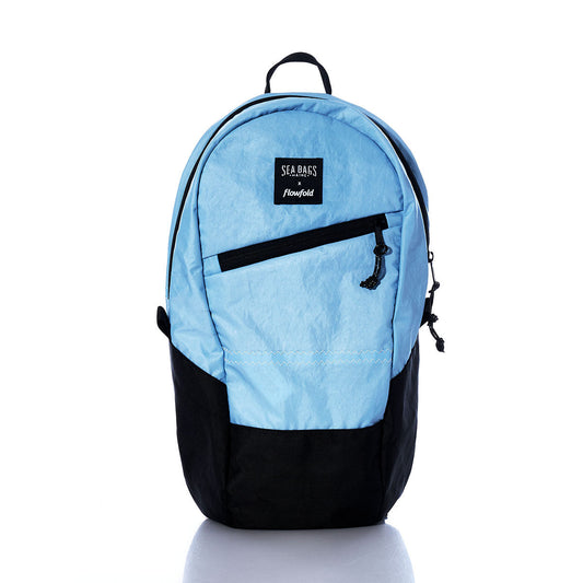 The Vintage Blue Crew Backpack by Sea Bags, featuring a light blue and black design crafted from recycled sail cloth, includes a front zipper pocket, top handle, and a SEA BAGS flowfold label, displayed on a white background. by Sea Bags