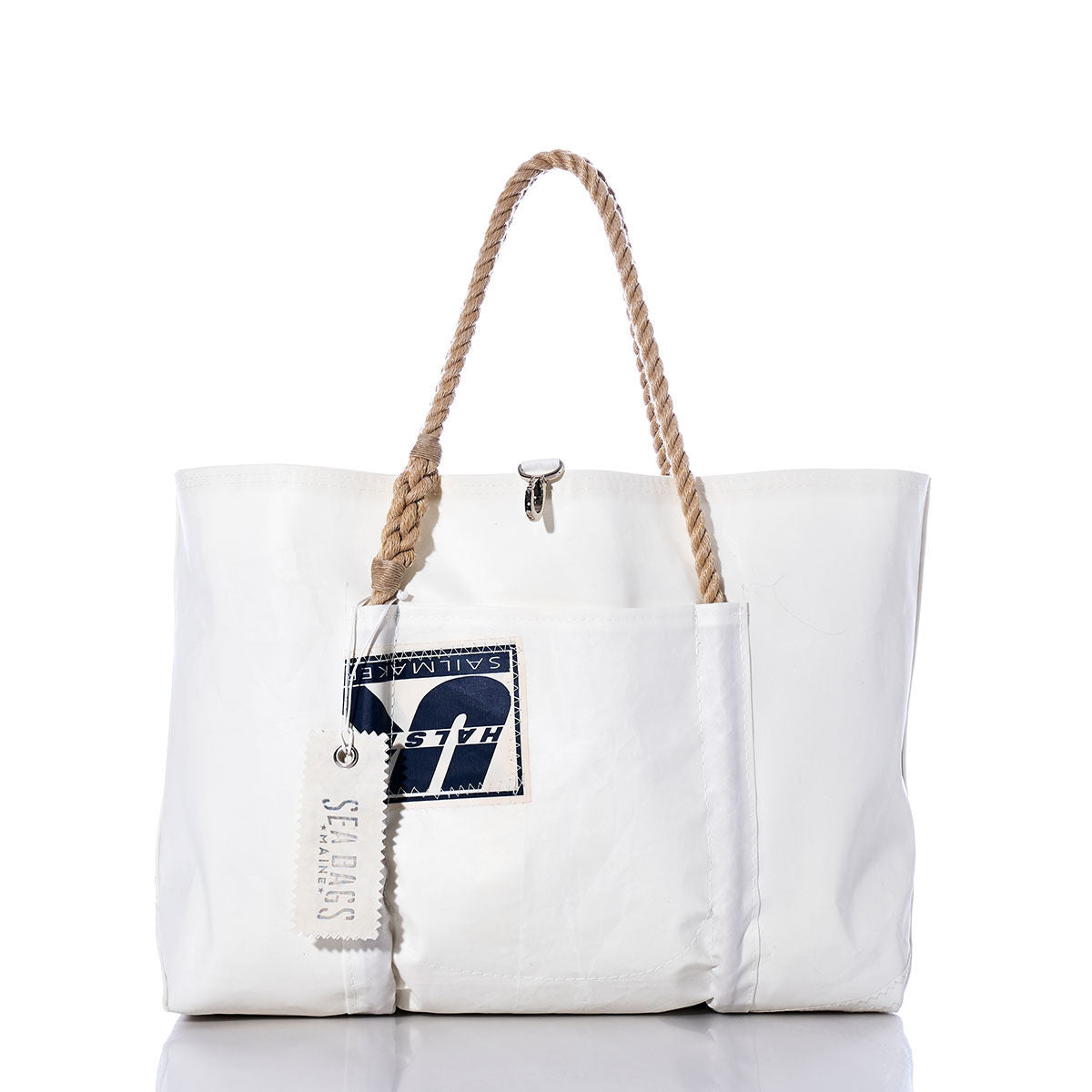 The Vintage Halsey Sailmakers Wharf Tote by Sea Bags is expertly handcrafted in Portland, Maine, from durable recycled sailcloth. This white tote features sturdy rope handles, a distinctive patch with the number 7, and a small SEA BAGS tag—blending nautical style with lasting quality. by Sea Bags