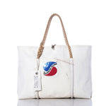 Sea Bags’ Vintage Sobstad Sailmakers Wharf Tote is a handcrafted white tote bag made from recycled sailcloth, featuring sturdy rope handles, a front patch with a red and blue logo, and a hanging SEA BAGS tag. This Portland, Maine creation embodies timeless vintage style. by Sea Bags