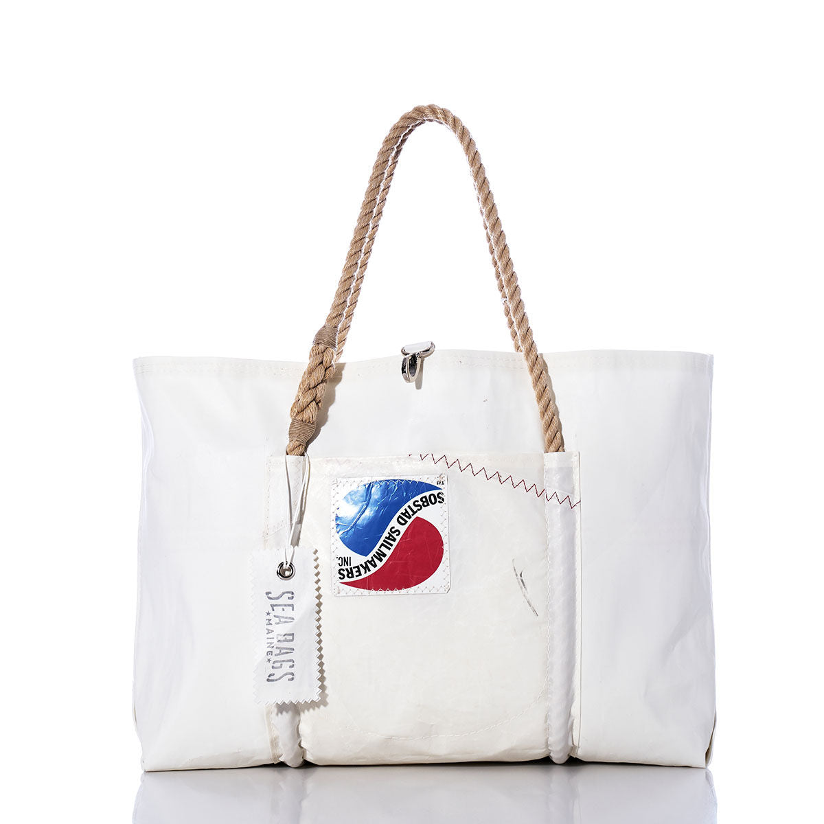 Sea Bags’ Vintage Sobstad Sailmakers Wharf Tote is a handcrafted white tote bag made from recycled sailcloth, featuring sturdy rope handles, a front patch with a red and blue logo, and a hanging SEA BAGS tag. This Portland, Maine creation embodies timeless vintage style. by Sea Bags