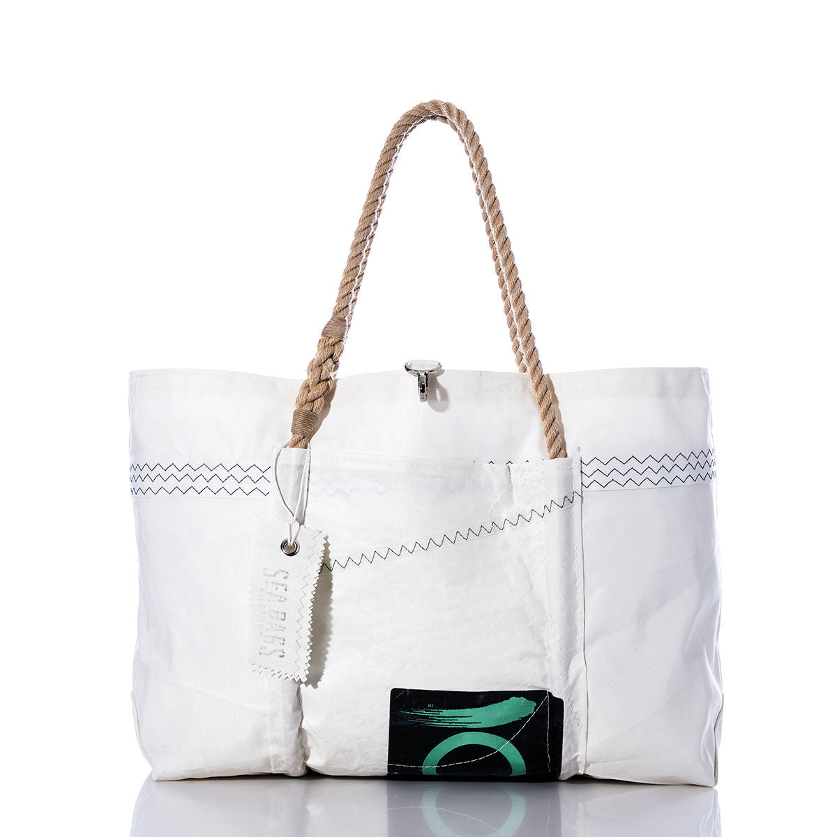 The Sea Bags Vintage Quantum Wharf Tote is a handmade white tote bag featuring brown rope handles, zigzag stitching, a small metal clasp, a white tag, and a black patch with a green design on the lower front. Crafted from recycled sail material, this distinctive style combines sustainability with signature nautical charm. by Sea Bags