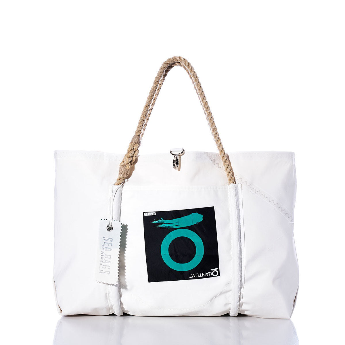 Sea Bags Vintage Quantum Wharf Tote with rope handles, featuring a front pocket adorned with a circular teal and black motif and a SEABAGS-labeled hanging tag, displayed against a white background. This handcrafted tote from Portland, Maine is made from recycled sail cloth, seamlessly blending style and sustainability. by Sea Bags