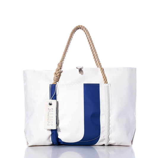 The Sea Bags Vintage Blue U Wharf Tote is a hand-crafted white tote bag featuring a sturdy rope handle, a bold blue letter U graphic, and a white tag on the front—beautifully photographed against a white background. by Sea Bags