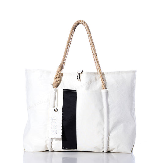 The Sea Bags Vintage Black Stripe Wharf Tote is a handcrafted white tote bag made from recycled sails in Portland, Maine. It features rope handles, an exterior pocket, a bold black vertical stripe, and a Sea Bags branded tag, all shown against a white background. by Sea Bags